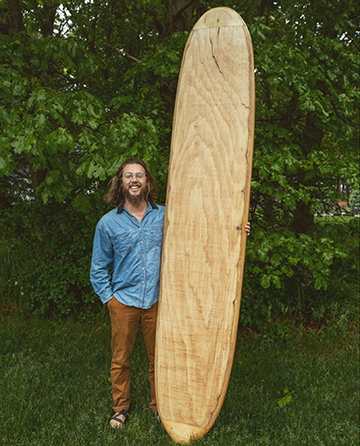 Carson Brown, with one of the wooden surfboards he created.