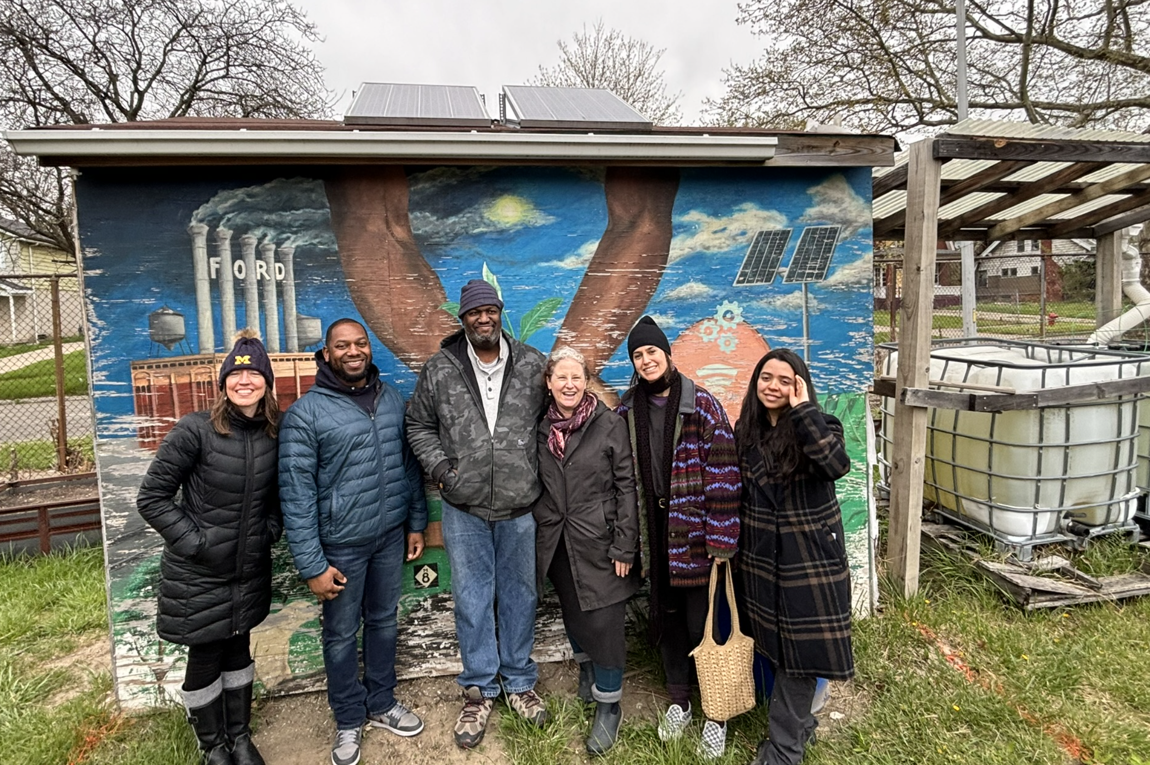 Clinic team poses with Clinic client, Juan Shannon of the Parker Village Foundation outside of its solar-powered greenhouse.