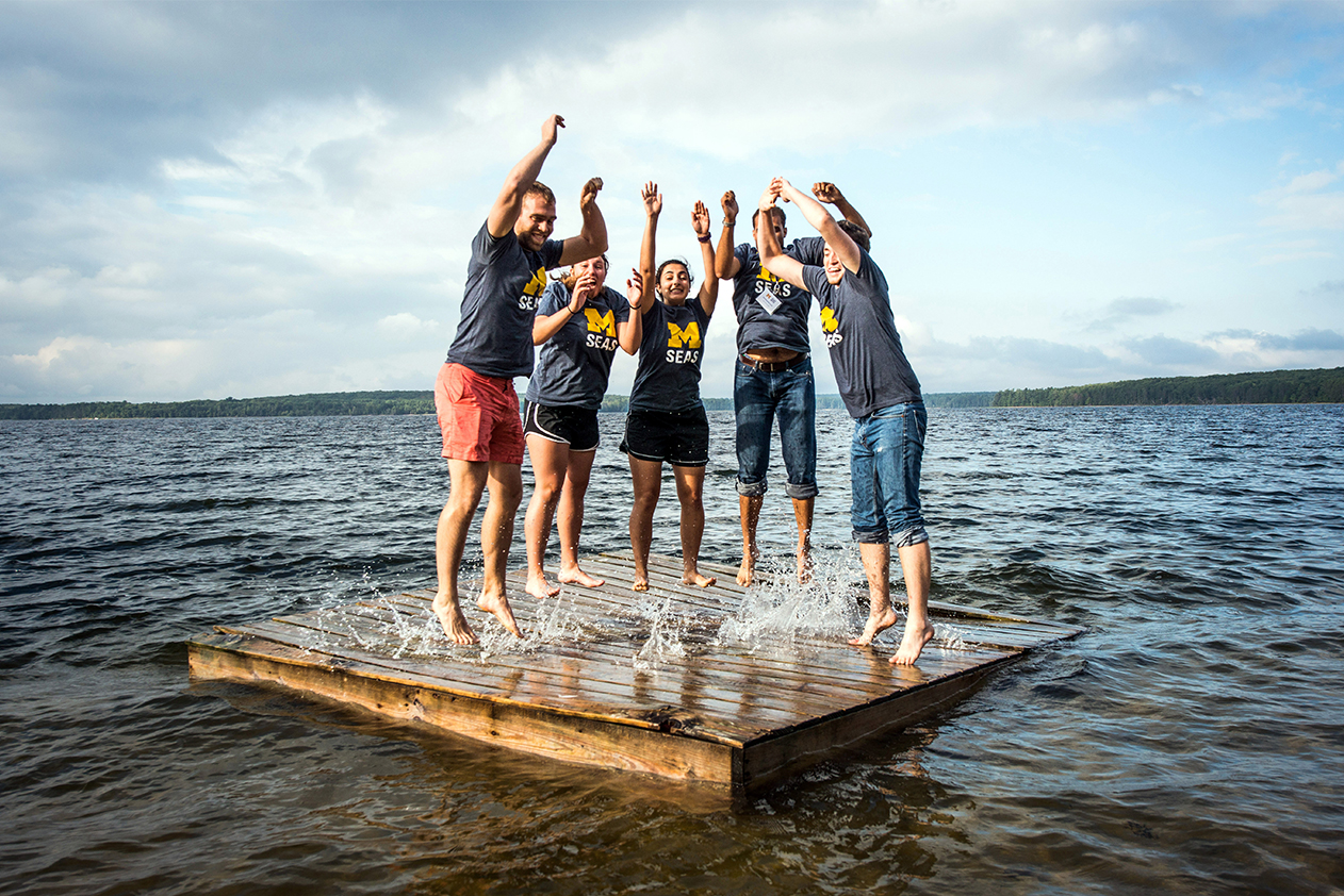 a group of student jumping on the dock in Douglas Lake
