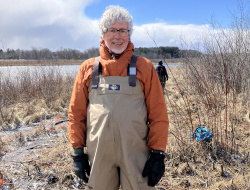 Portrait photo of project client Stephen Brown standing at the wetland during a site work day