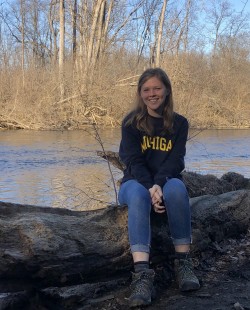 Allyson Holman sitting on a log by the Huron River