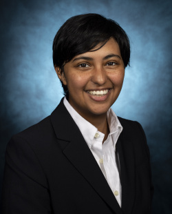 Image of a brown woman with short black hair in a blazer and a white shirt.