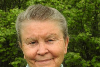 Jean MacGregor, smiling behind a green background