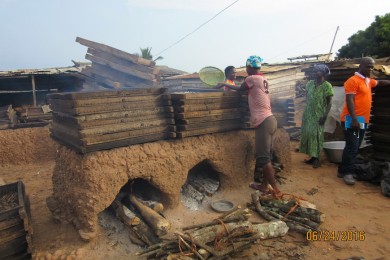  Firewood is loaded into the rudimentary mud ovens, and trays of fish are stacked on top for smoking, which is done to preserve the fish. Photo by Pam Jagger, University of Michigan.