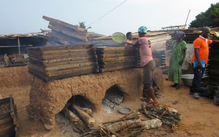  Firewood is loaded into the rudimentary mud ovens, and trays of fish are stacked on top for smoking, which is done to preserve the fish. Photo by Pam Jagger, University of Michigan.