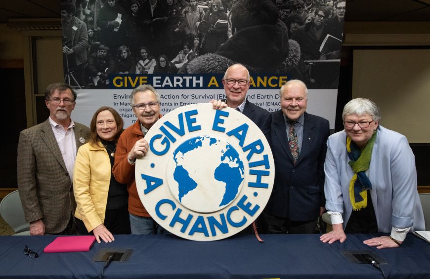 From left, panelists George Koling, Elizabeth Grant Kingwill, Doug Scott, David Allan, Arthur Hanson and Barbara Alexander pose with the emblem from the original 1970 Teach-In on the Environment. (Photo by Dave Brenner, School for Environment and Sustainability)